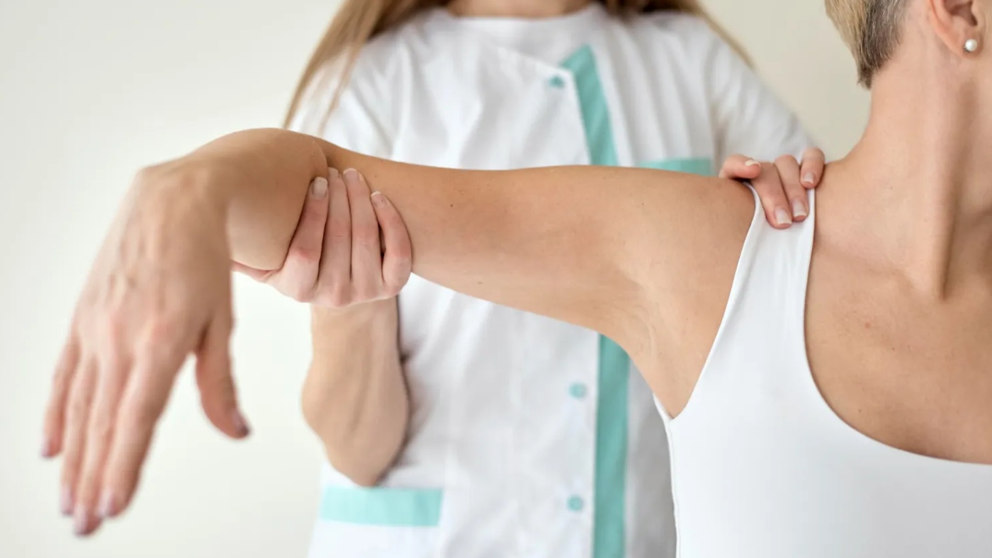 fisio sujetando el brazo de una paciente fisio sujetando el brazo de una paciente