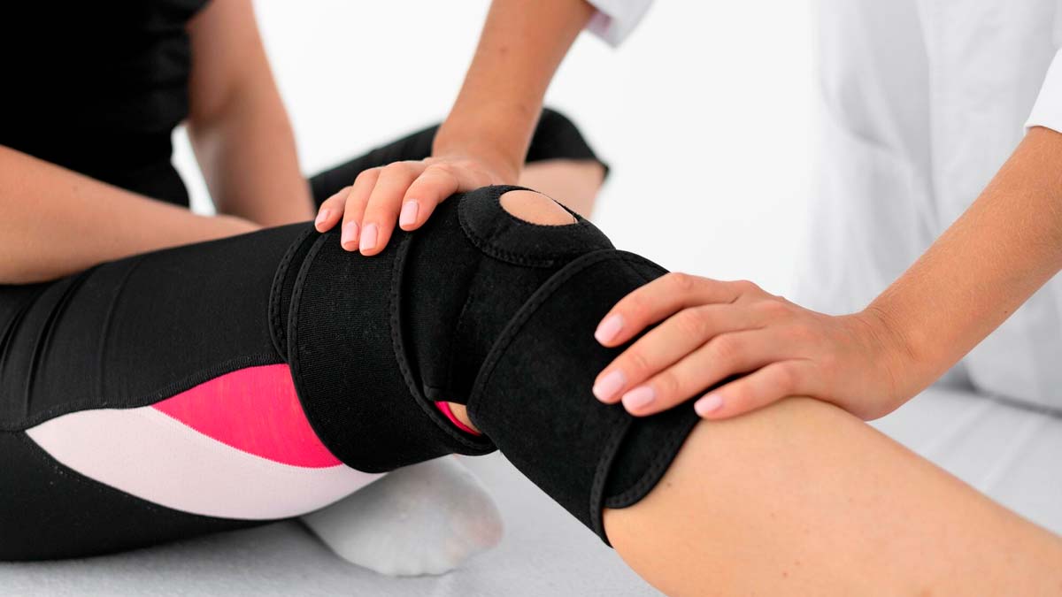 fisioterapeuta tocando la rodilla de una paciente