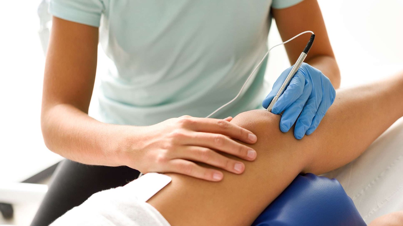 fisio aplicando fisioterapia invasiva en la rodilla de un paciente
