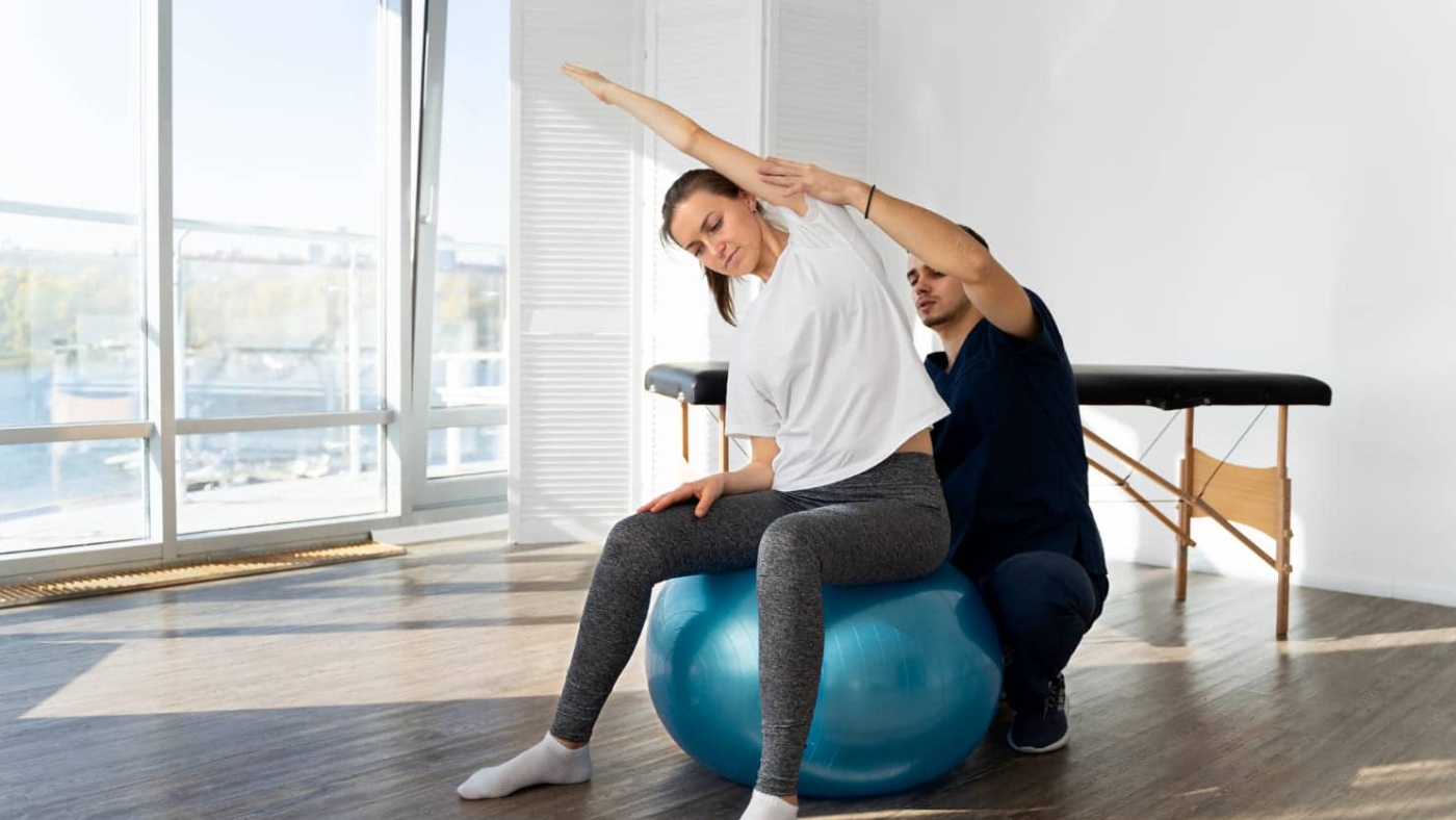 paciente sentada sobre un balon de pilates